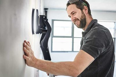 Mann verwendet die Planex mit Licht, um eine Wand zu schleifen