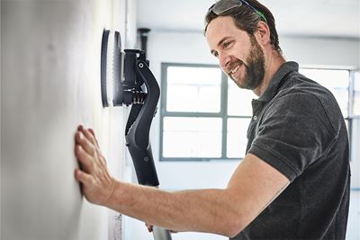 Handwerker bearbeitet Wand mit dem Planex Langhalsschleifer mit Beleuchtung