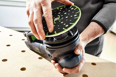 Ein Handwerker setzt den Schleifteller auf einen Festool Schleifer