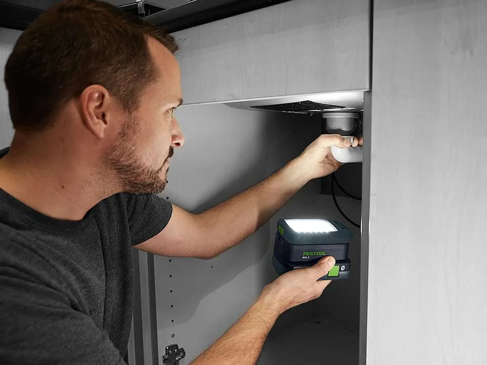 Ein Mann leuchtet mit der SYSLITE KAL 2 die Verbindung eines Waschbeckens aus