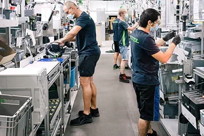 Im großzügigen Werk montieren Mitarbeiter an modernen Arbeitsstationen Elektrowerkzeuge.