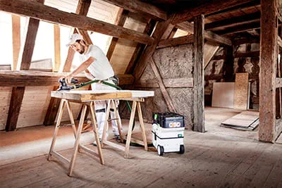 Marco Dworzak arbeitet Fenster und Rahmen mit dem Akku-Schleifer von Festool ab, dabei hilft das neue Akku-Absaugmobil CLEANTEC CTLC MINI