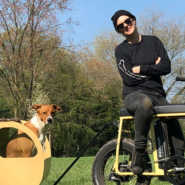 Die Makerin Laura Kampf auf einem selbstgebauten Fahhrad mit ihrem Hund Smudo in einem Tiny Trailer.