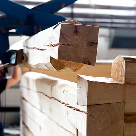 Ein Holzbalken wird mit dem Kran an Ort und Stelle gebracht.